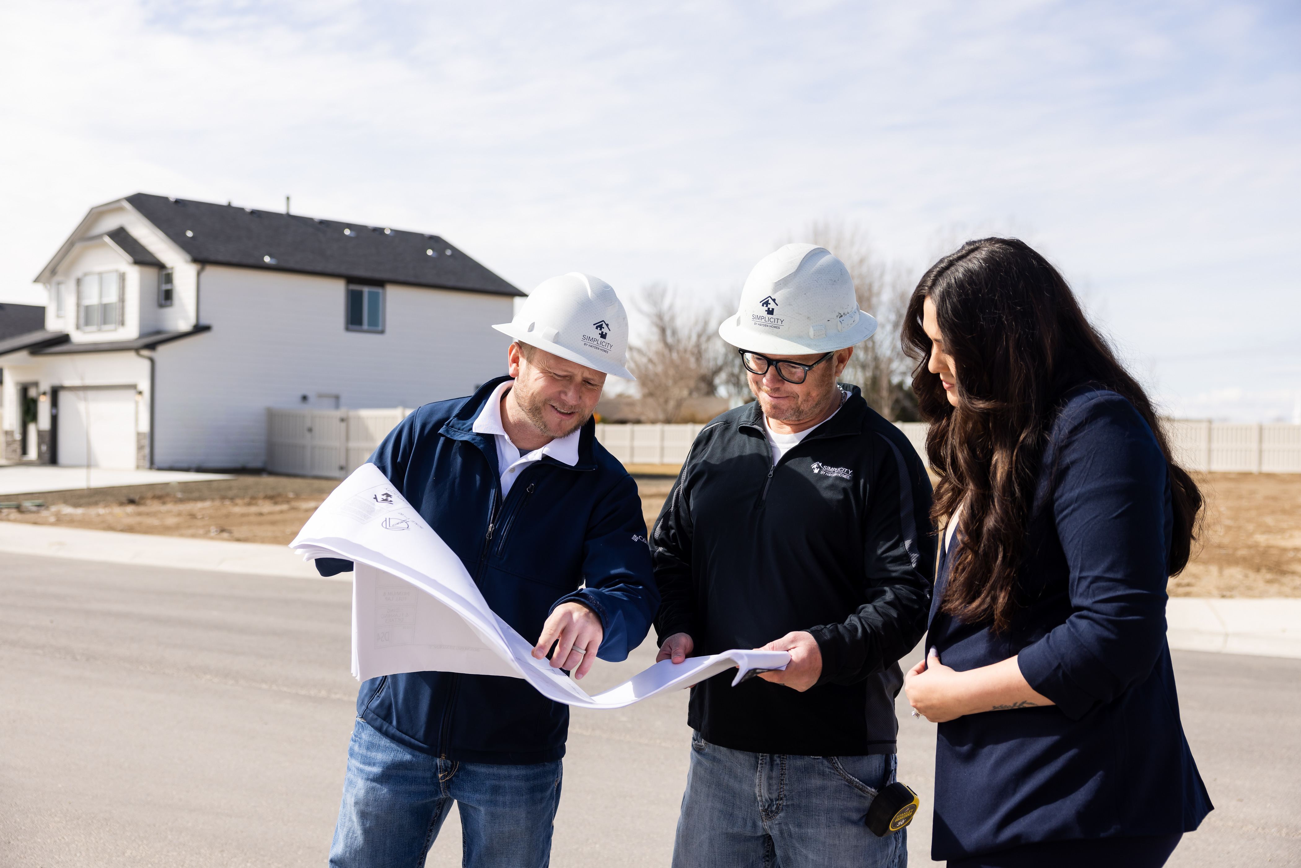 How to Buy Land to Build a New Home. Two Simplicity Homes employees reviewing plans with homebuyer