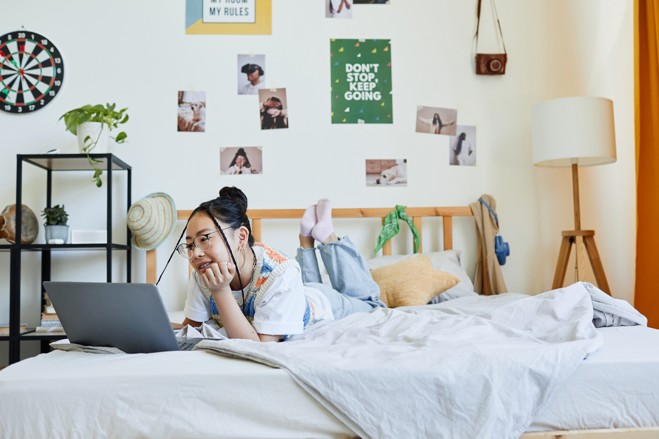 Portrait of teenage Asian girl using laptop on bed in cozy room interior. Designing a Kid’s Room that Lasts